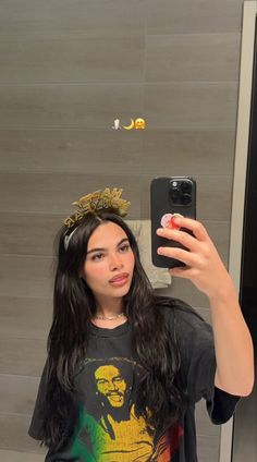 a woman taking a selfie in front of a mirror wearing a crown and t - shirt