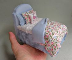 a hand holding a small doll bed with flowers on it