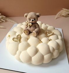 a teddy bear sitting on top of a white cake