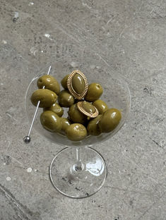 a glass bowl filled with olives on top of a table