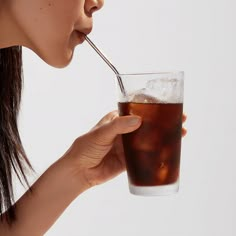 a woman drinking soda from a glass with a straw sticking out of it's mouth