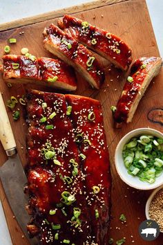 ribs covered in bbq sauce, green onions and sesame seeds on a cutting board