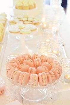 a table topped with lots of desserts and cookies on top of glass dishes covered in frosting