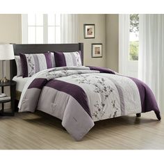 a bed with purple and white comforters in a room