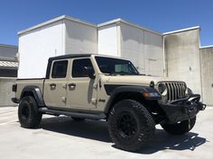 a beige jeep parked in front of a building with no doors on it's sides