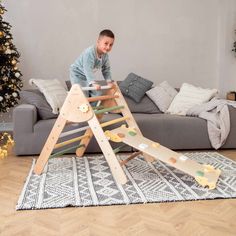 a young boy playing on a wooden ladder in front of a couch and christmas tree