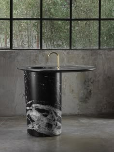 a black and white marble sink in front of a large window with plants outside it