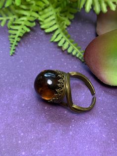 A beautiful dark amber colored crystal ball set in either an antique bronze or silver crown setting. Crystal ball measures approximately 16mm. Coloration may slightly vary but you will receive a crystal ball similar to the one in the photo. Ring is adjustable. To keep your plated jewelry in good condition, avoid contact with water, perfume, lotions, sweat, and sprays! Adjustable Brass Crystal Ring For Gift, Vintage Adjustable Crystal Ring For Gift, Elegant Adjustable Brass Crystal Ring, Magic Crystal Ball Ring, Crystal Ball Earrings, Amber Crystal, Bug Art, Magic Ring, Silver Crown