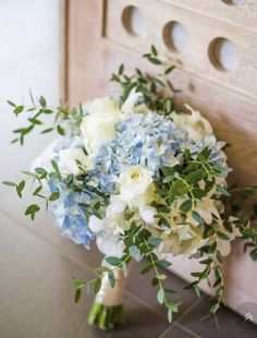 a bridal bouquet sitting on top of a counter next to a wooden door with holes in it