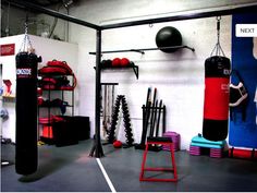 a gym with punching bags, boxing gloves and exercise mats on the wall next to each other