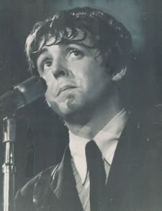 a man in a suit and tie standing next to a microphone with his mouth open