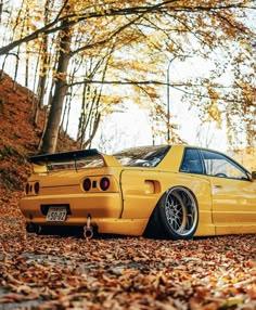 a yellow car parked on the side of a leaf covered road