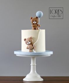 there is a cake with two teddy bears on it and a balloon in the air