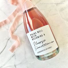 a bottle of pink wine sitting on top of a marble counter next to a ribbon