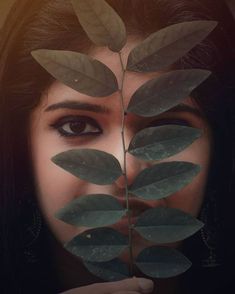 a woman with leaves on her face looking through the hole in front of her eye