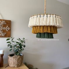 a light hanging from a ceiling with tassels on the end and a potted plant next to it