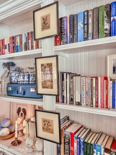 a bookshelf filled with lots of books next to a white shelf topped with pictures