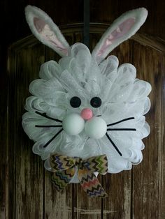 a white bunny head hanging on the side of a wooden door with a bow tie