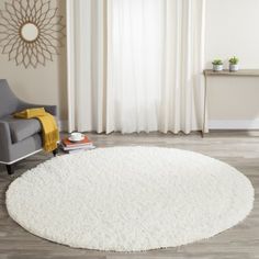 a living room with a chair and rug in front of a window that has white curtains