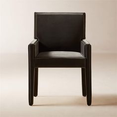 a black leather chair sitting on top of a white floor next to a beige wall