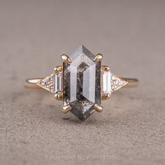 a white and yellow gold ring with an emerald cut diamond surrounded by three baguettes