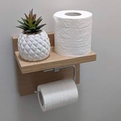 a pineapple and toilet paper on a wooden shelf