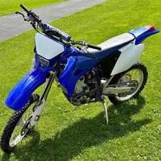 a blue and white dirt bike parked in the grass