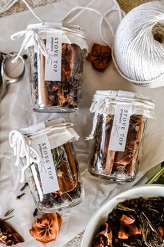 three jars filled with spices next to a ball of twine and yarn on top of a table