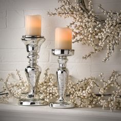 two silver candles are sitting on a mantle