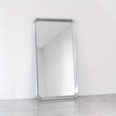 a mirror sitting on the floor in front of a white wall