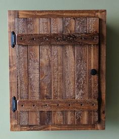 an old wooden door is mounted on the wall with two black knobs in it