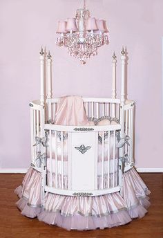 a white crib with a chandelier hanging from it's ceiling and pink walls in the background