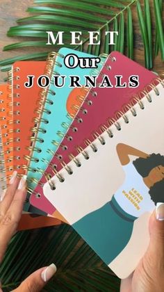 someone holding up a spiral notebook with the words meet our journals on it and palm leaves in the background