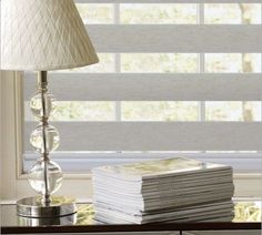 a lamp sitting on top of a table next to a stack of books and magazines