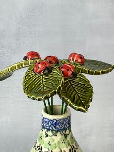 four ladybugs sitting on top of a leafy plant in a ceramic vase