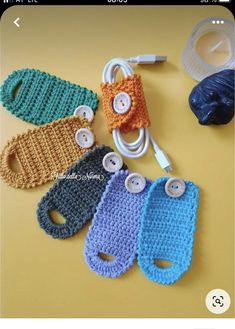 crocheted cell phone cases are sitting on a table with earbuds attached to them