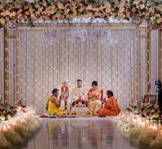 a group of people sitting around each other in front of a stage with candles and flowers