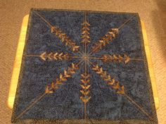 a blue and brown piece of cloth with an arrow design on the center, sitting on top of a wooden table