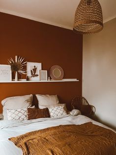 a bed with pillows and blankets on top of it next to a wall mounted shelf