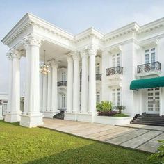 a large white house with columns and green awnings on the front lawn area