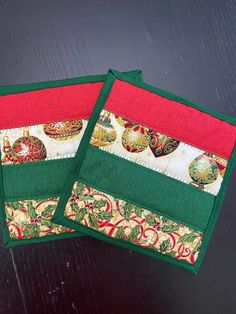 two green and red placemats sitting on top of a wooden table next to each other