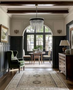 a living room filled with furniture and a chandelier hanging from the ceiling next to a window