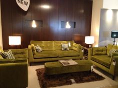 a living room filled with green couches and pillows on top of a white rug