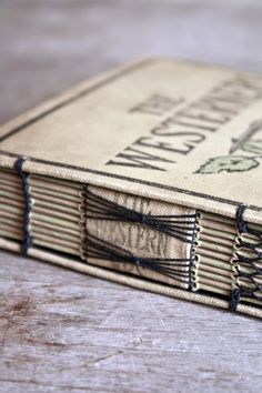 an old book is sitting on a wooden table with black stitching around the edges