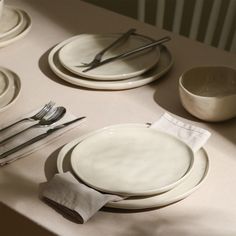 the table is set with white plates and silverware