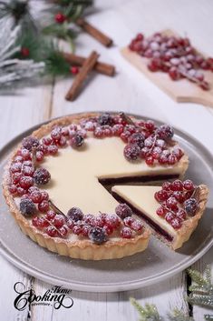 a cheesecake topped with berries on top of a metal plate next to christmas decorations