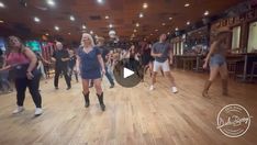 a group of people are dancing in a dance studio with lights on the ceiling and wooden floors