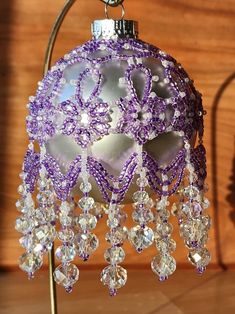 a purple ornament hanging from a metal stand on a wooden surface with beads