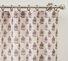 the curtain is hanging in front of a white wall with red and blue flowers on it