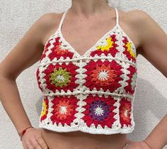 a woman is wearing a crocheted top with flowers on it